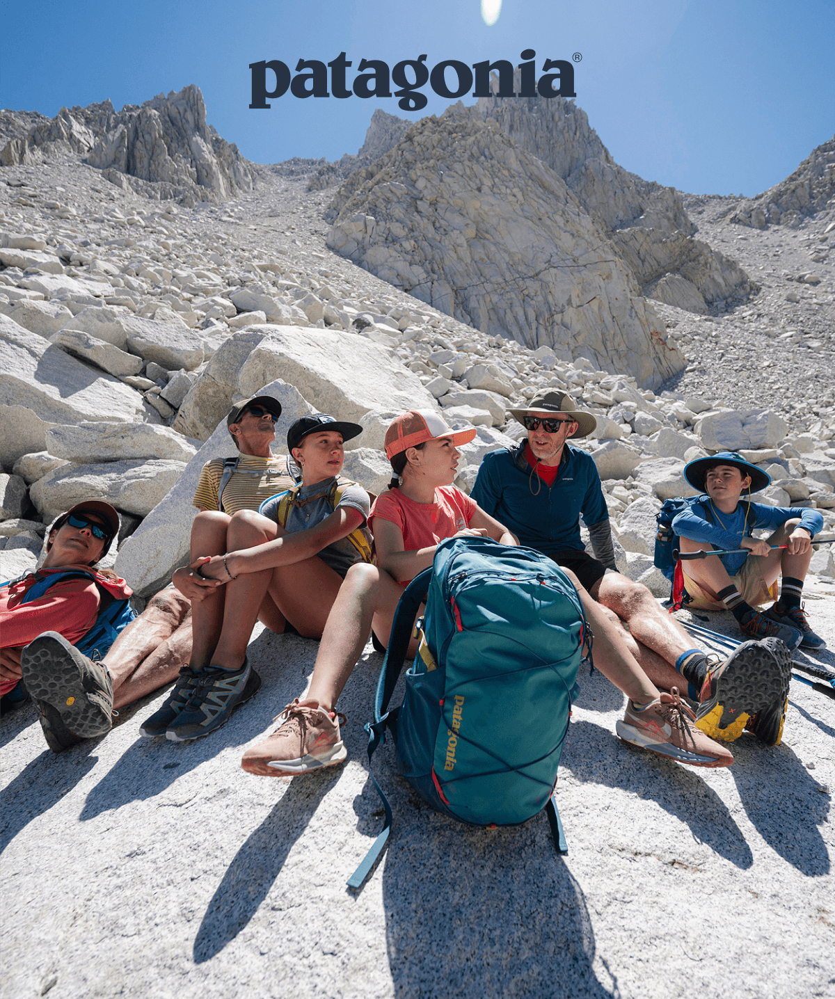 Six people sit on granite above timber line.