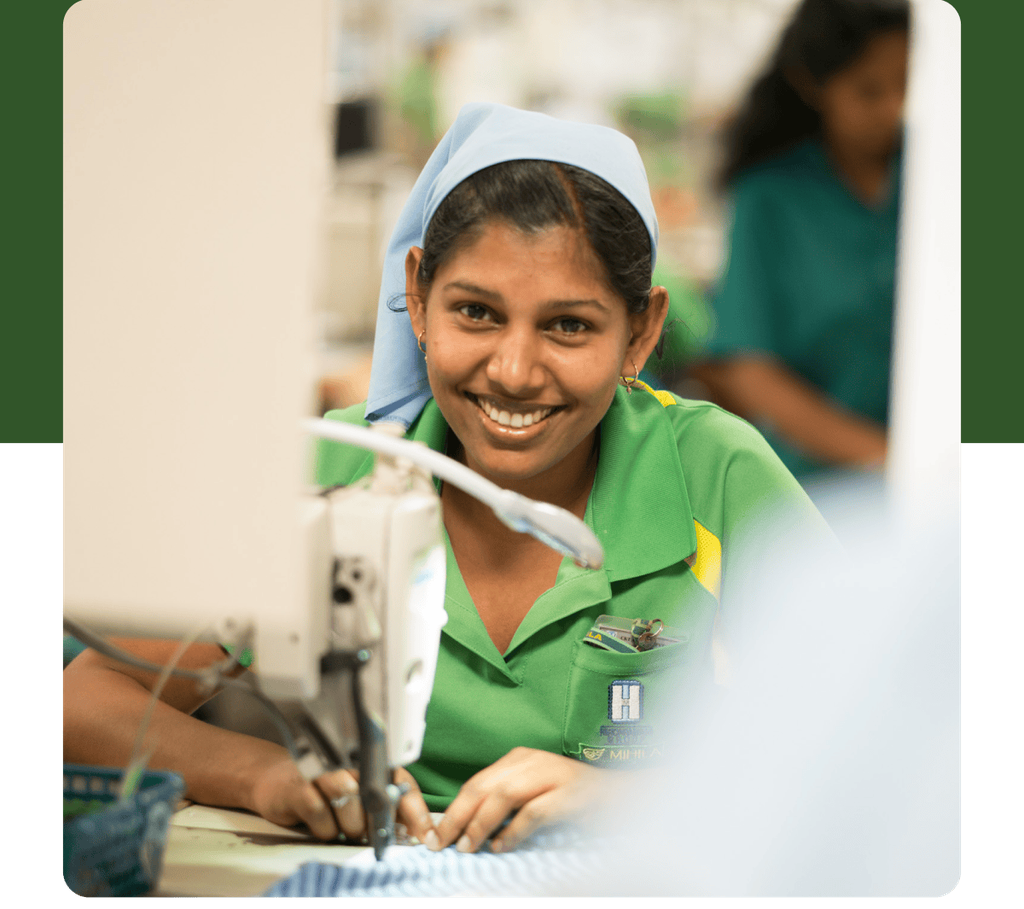 A person sewing a garment in a factory. 