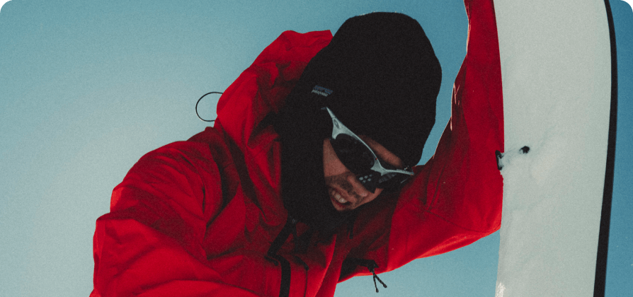 Nicholas Wolken adjusting ski bindings in a snowy setting.