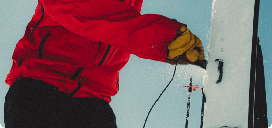 Nicholas Wolken adjusting ski bindings in a snowy setting.