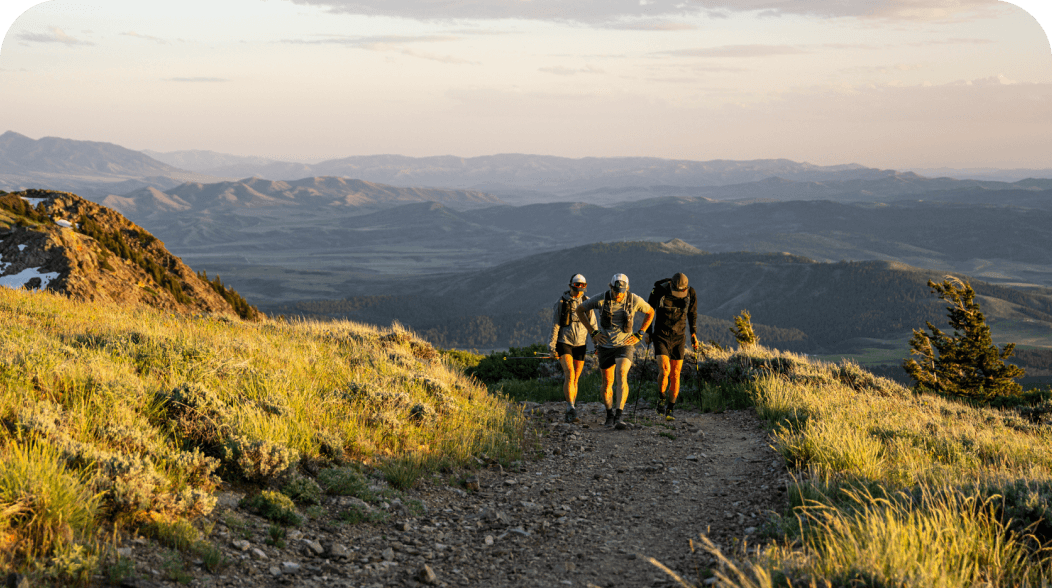 Three runners walk up a trail together.