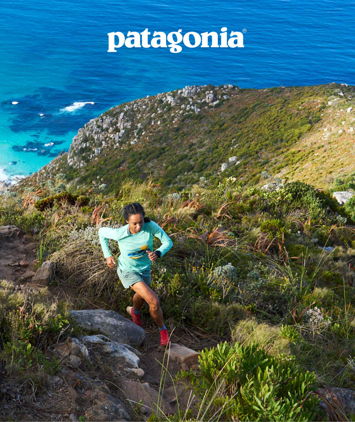  Patagonia. A person running up a steep trail on a cliff above the ocean.